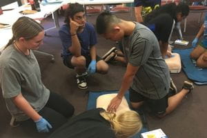 Aboriginal boys practising CPR and emergency response with a manikin