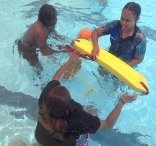 Aboriginal youth passing a lifeguard rescue tube in the pool at Jigalong