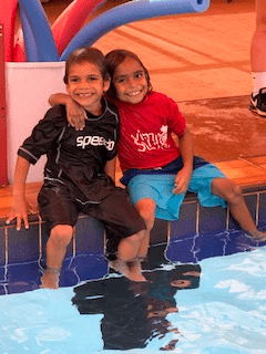 Two Martu boys with arms around each others shoulders sitting on the edge of the pool at Newman