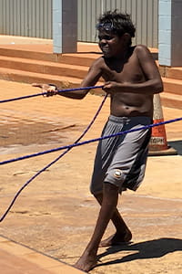 Child standing on pool deck pulling a rope