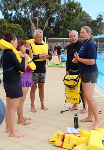 adults wearing lifejackets in training exercise at swimming pool