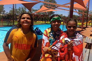 three Aboriginal children standing in front of a swimming pool