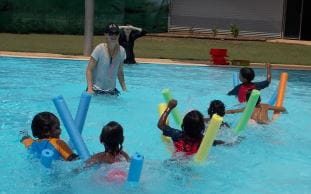 aboriginal children taking part in a pool noodle race with an instructor at Warmun Pool