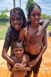 Three smiling children at Warmun community pool