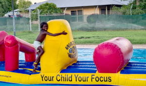 An Aboriginal boy on an inflatable witht he words Your Child Your Focus written on the side