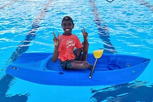 Indigenous child sitting on a kayak and smiling at the camera