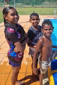 Three Warmun children smiling at the local pool