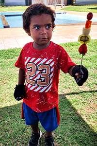 little Aboriginal boy holding a fruit skewer