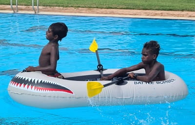 two Aboriginal boys in an inflatable boat in a pool