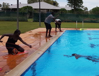 A young Aboriginal woman using a rope to rescue a course participant in the Warmun pool