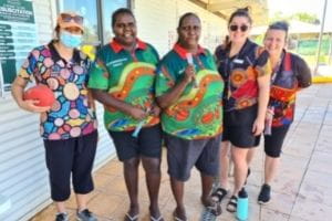 Five women wearing colouful Aboriginal print shirts