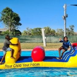 Two Aboriginal boys having fun on a pool inflatable
