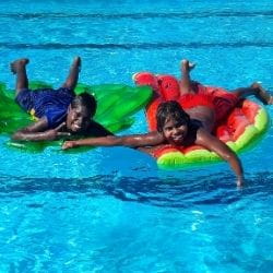 Two Aboriginal boys on inflatables in the pool