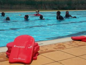 Aboriginal children int he pool with their instructor at Warmun with red kickboards by the pool