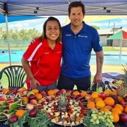 Steve and Aisyah Waterman standing behind a table full of fruit