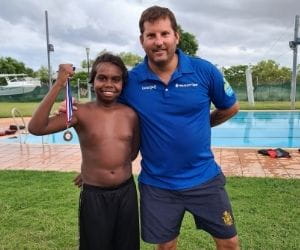 An Aboriginal boy holding his medal with Pool Manager Stephen Waterman