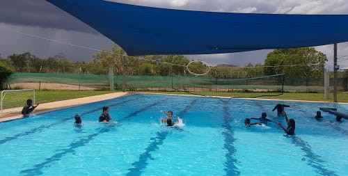 Warmun children playing water polo in their local pool as a storm rolls in