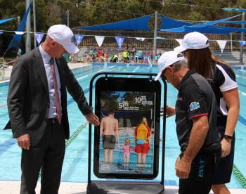 Sean L'Estrange - Member for Churchlands, LIWA President Jeff Fondacaro and Royal Life Saving's Lauren Nimmo looking at a Watch Around Water sign by the pool at Bold Park Aquatic Centre