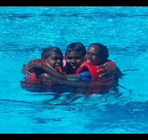 Three chidren in a huddle learning water safety
