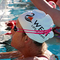 A woman wearing a West Life Saving swim cap in the pool