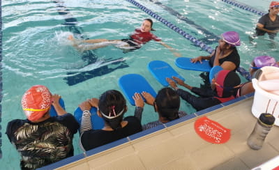 A swim instructor in the pool with a group of women