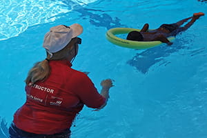 Swim Instructor Sandra McKenzie with a child using a pool noodle to float