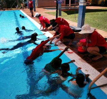 Aboriginal children in the pool with instructors teaching them swimming skills