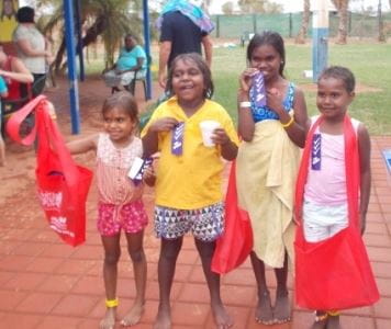 Four aboriginal children standing by the pool at Yandeyarra with their certificates and Swim and Survive bags