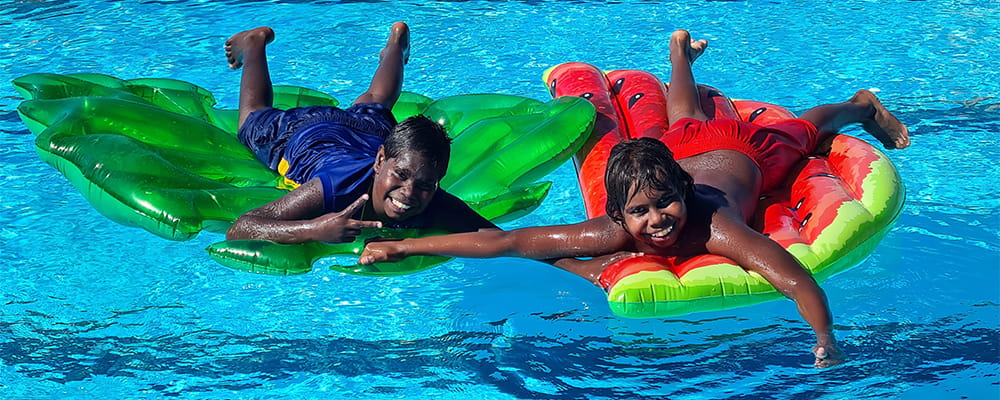 two Aboriginal children on pool inflatables