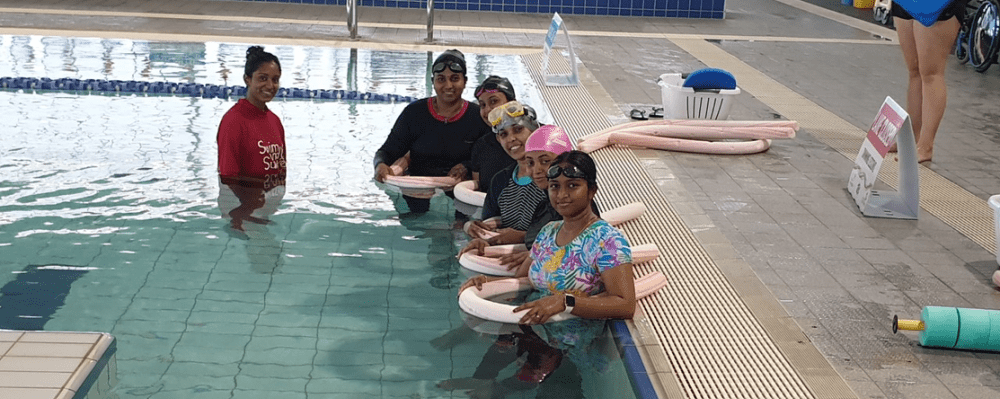 A group of multicultural women in the pool with their Swim and Survive instructor