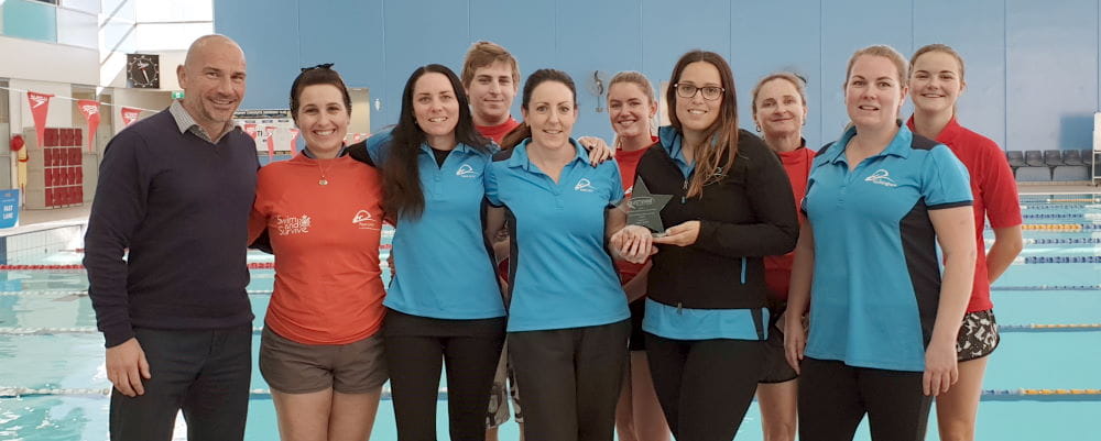 Aqua Jetty's swim school team standing by the pool with their AUSTSWIM award