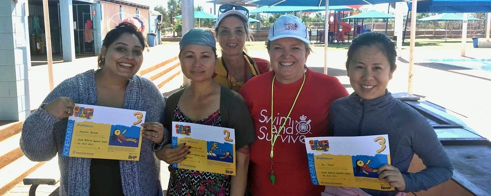 multicultural women with their swimming instructor holding swimming certificates