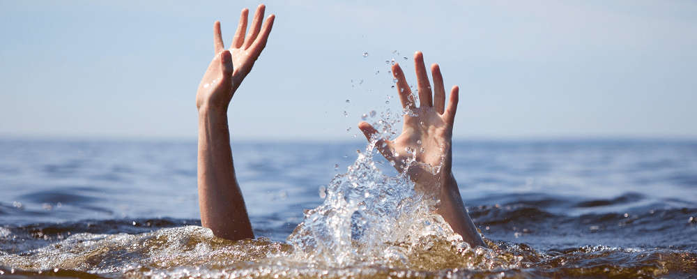 person underwater with hands up signalling for help