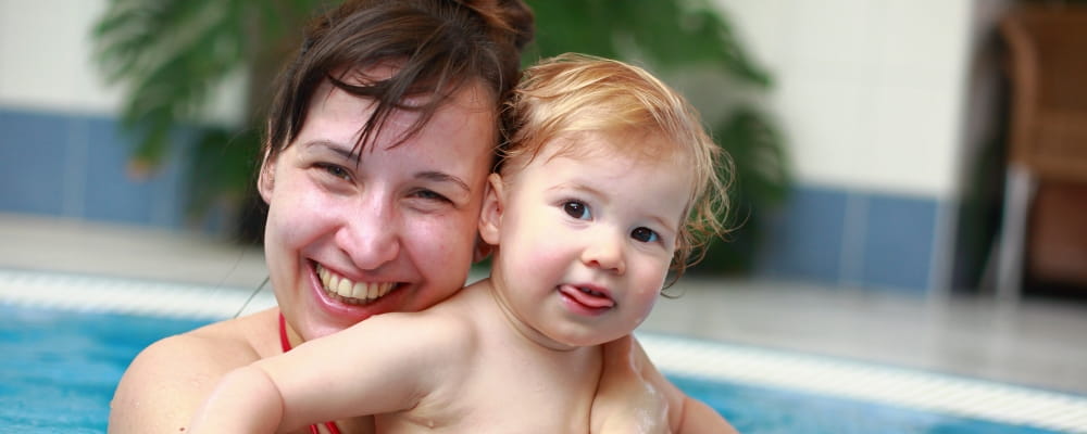 a mum cuddling baby boy in the pool