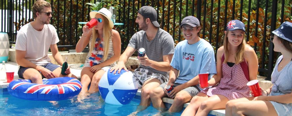 A group of young people around the pool with Australia Day accessories and drinks