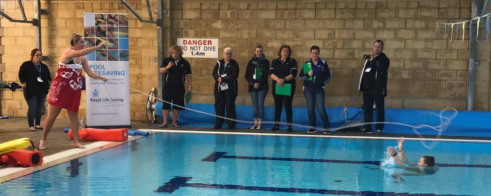 Sarah Hamilton demonstrating rope throw tp a person in the pool at the AUSTSWIM conference