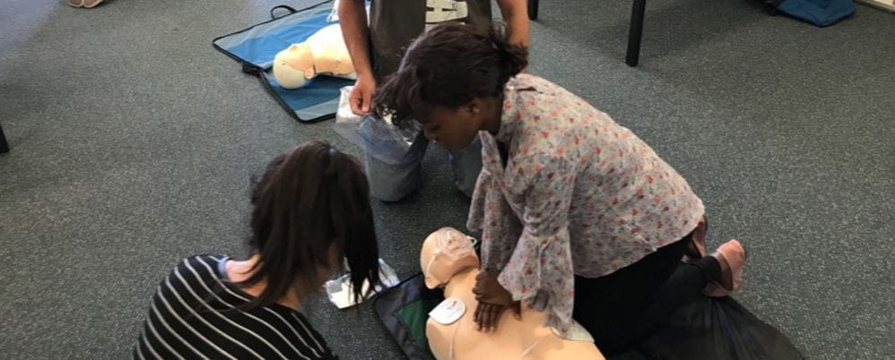 Two ladies perform CPR on dummy
