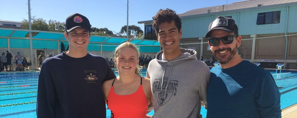 three young pool lifesaving athletes with their coach