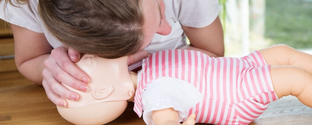 a woman practising CPR on an infant manikin
