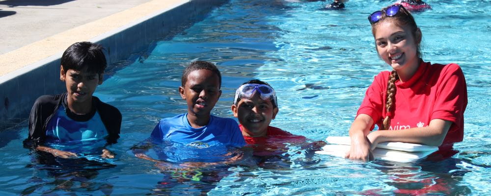 Three multicultural boys with a female swim instructor in the pool at Balcatta Senior High School