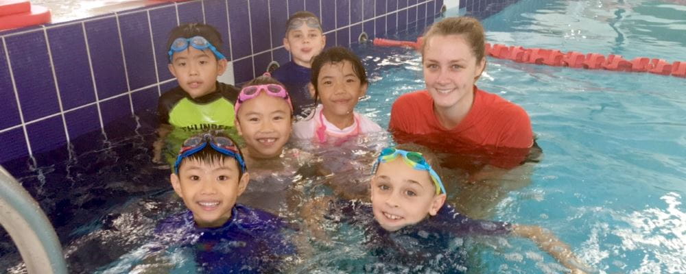6 mulitcultural children with their swim instructor in the pool at Ballajura Aquatic Centre