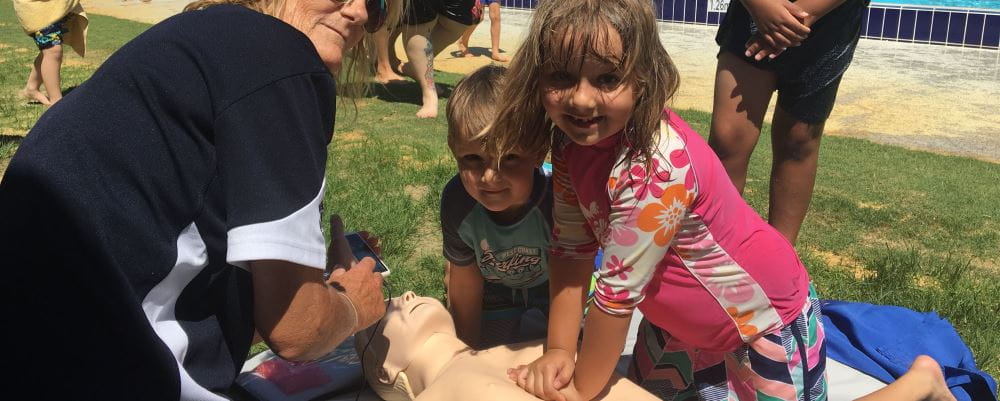 Little girl performing CPR on a manikin