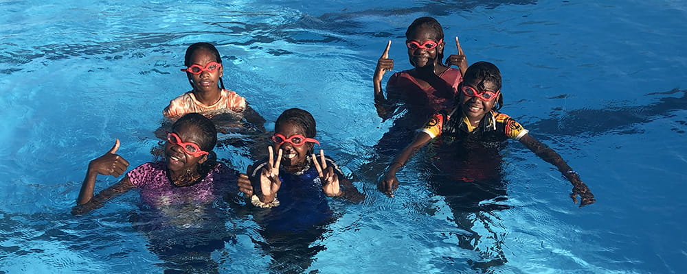 Five Aboriginal children in the water wearing goggles at the Bidyadanga Community Pool