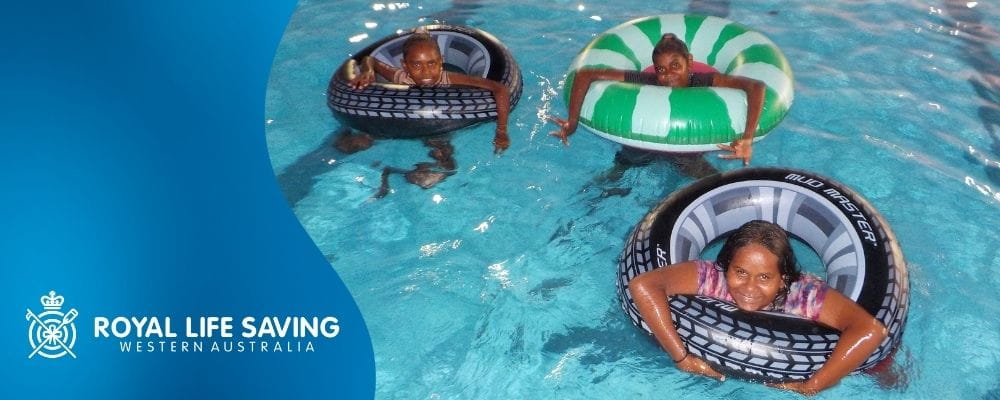 Three Aboriginal children on floaties in a pool