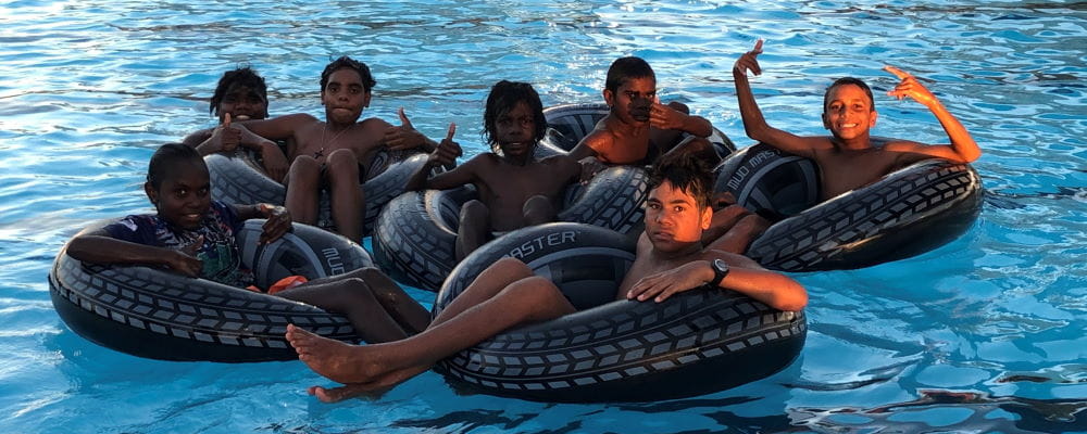 Aboriginal children sitting on inflatable tubes in the pool
