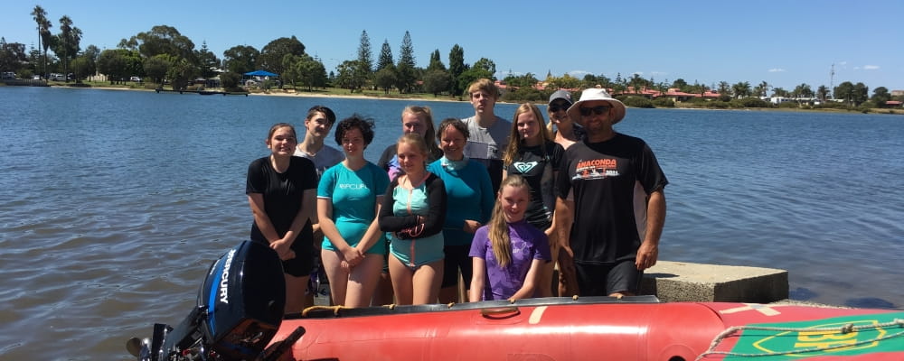 a group of young people in the Leschenault Inlet next to a boat 