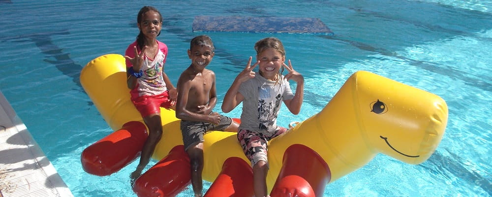 three Aboriginal children on a pool inflatable