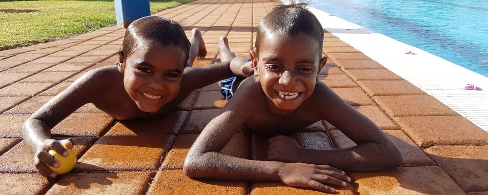 Two aboriginal boys laying on the ground by the pool at Burringurrah
