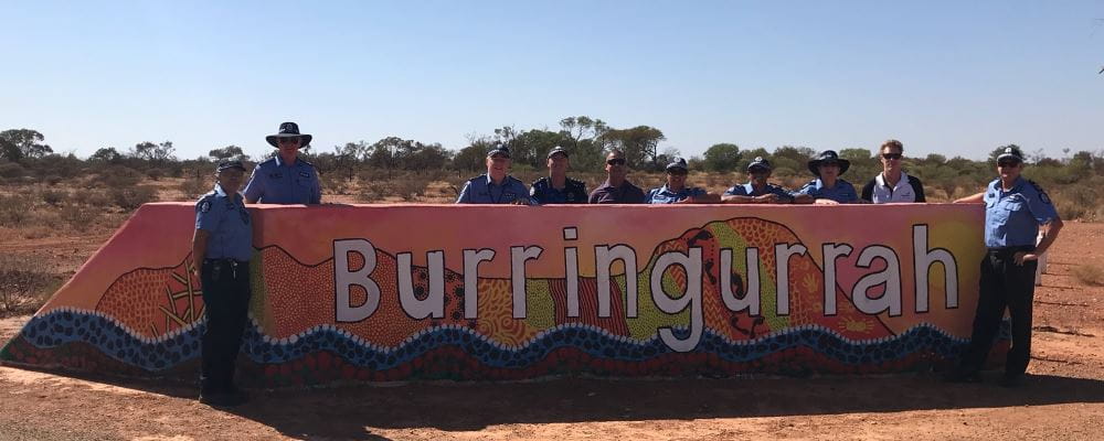 Police and RLSSWA's Greg Tate standing by the Burringurrah sign surrounded by red dirt