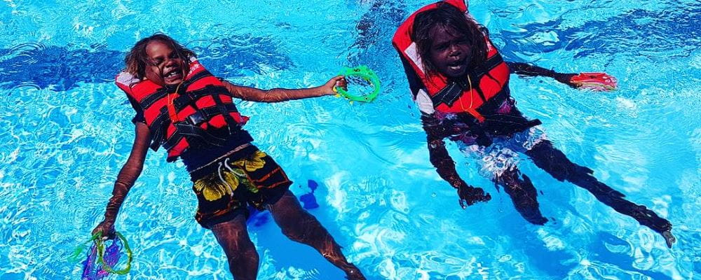 Two aboriginal children wearing lifejackets enjoying a swim at Burringurrah